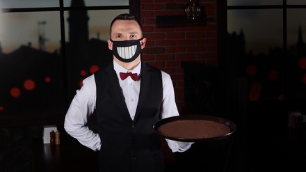 Ein Kellner mit Mundschutzmaske