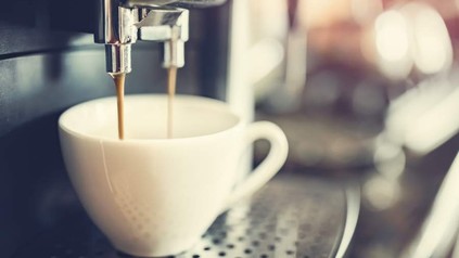 Kaffee läuft aus einer Kaffeemaschine in eine Tasse