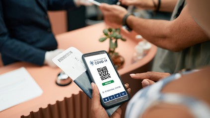 Urlauber zeigen Impfzertifikat an der Hotelrezeption