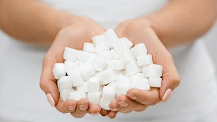 Eine Frau die einige Würfelzuckerstücke in den Händen hält