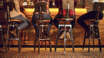 Vier Männer sitzen an einer Bartheke