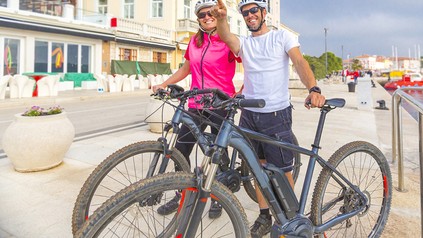 Ein Pärchen mit Mountainbikes vor einem Hotel
