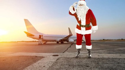 Ein Weihnachtsmann steht vor einem Flugzeug an einem Flughafen