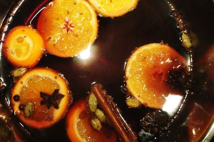 Ein Topf mit Glühwein, in dem Anis, Orangen und Zimtstangen schwimmen