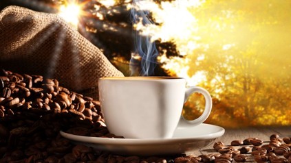 Dampfende Tasse Kaffee mit Kaffeebohnen rundherum