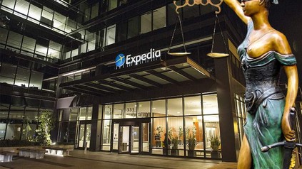 Das Bürogebäude von Expedia von außen und eine Justitia Statue daneben
