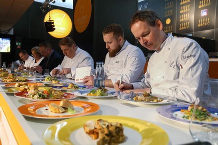 Mehrere Köche probieren verschiedene Speisen und machen sich Notizen für die Bewertung