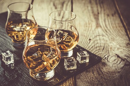 Drei Whiskygläser mit Eiswürfeln und Whisky