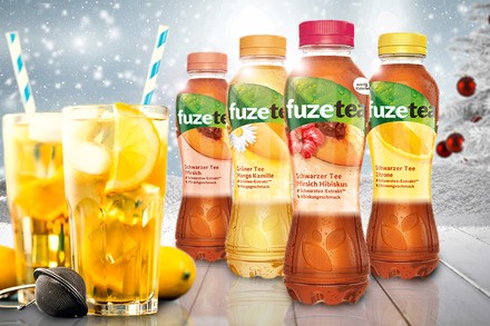 Vier verschiedene Flaschen fuzetea, Schwarzer Tee Pfirsich, Grüner Tee Mango Kamille, Schwarzer Tee Pfirsich Hibiskus und Schwarzer Tee Zitrone, davor stehen zwei Gläser mit Eistee, Eiswürfen und Strohhalm