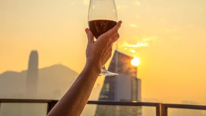 Eine Hand hält ein halbvolles Glas Wein hoch