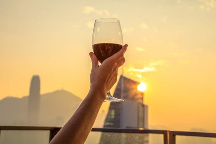 Eine Hand hält ein halbvolles Glas Wein hoch