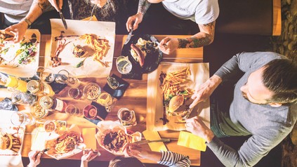 Personen an Esstisch mit Fastfood