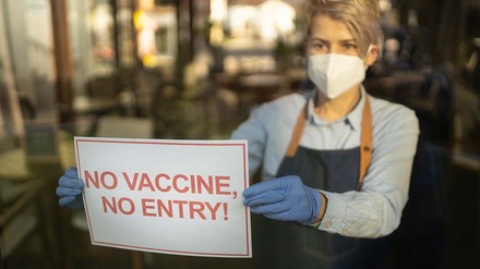 Gastronomin hängt Schild an die Restauranttür