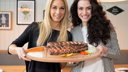 Yvonne Rueff und Kimberly Budinsky halten ein Holzbrett mit Rippchen