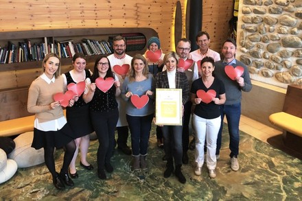 Karin Leeb, Martin Klein und die Mitarbeiter des Hochschober-Teams halten Herzen und die Urkunde von HolidayCheck in den Händen
