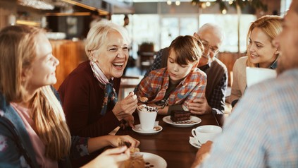 Familie mit Großeltern und Kind sitzen lachend im Restaurant