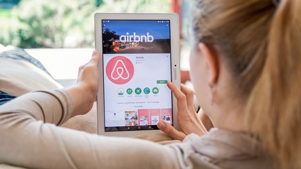 Junge Frau installiert die Airbnb-App auf einem Tablet