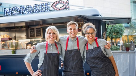 Drei Auszubildende vor einen Sstreetfood-Wagen von Nordsee