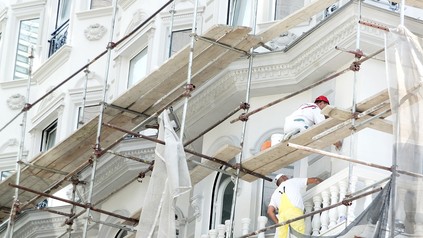Bauarbeiter auf einem Baugerüst vor einem Gebäude