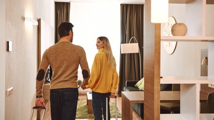 Pärchen betritt Händchen haltend ein Hotelzimmer