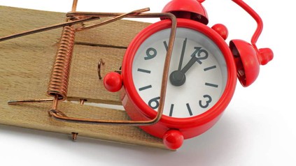 Ein Wecker steckt in einer Mausefalle fest