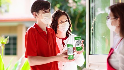 Junge und Mutter zeigen ihrem Impfnachweis an der Restauranttür