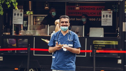 Pfleger oder Klinikmitarbeiter mit Mundschutz holt sich Essen von einem Foodtruck