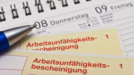 Arbeitsunfähigkeitsbescheinigungen liegen auf einem Kalender
