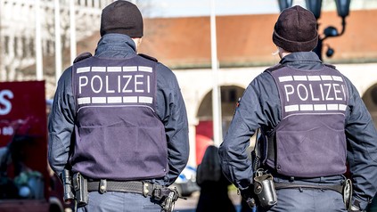 Zwei Polizisten in Schutzkleidung mit dem Rücken zugewandt
