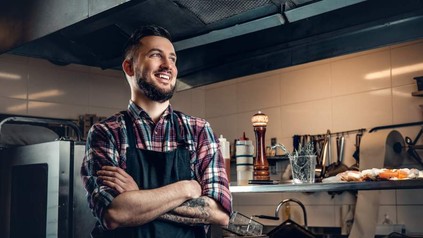 Ein junger Koch steht zufrieden in einer Küche