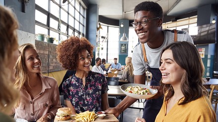 Kellner bringt Gästen im Restaurant das Essen an den Tisch