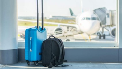 Ein Koffer und ein Rucksack stehen in einer Wartehalle am Flughafen