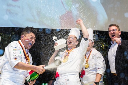Köche feiern auf der Bühne mit einer Flasche Sekt