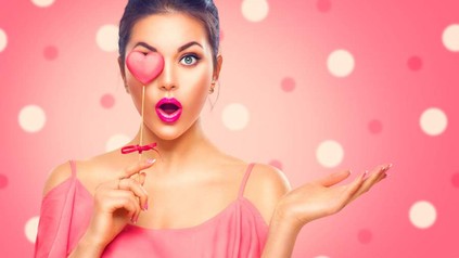 Frau hält sich ein künstliches Herz vor ihr rechtes Auge