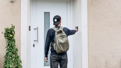 Mann mit Rucksack klingelt an Haustür