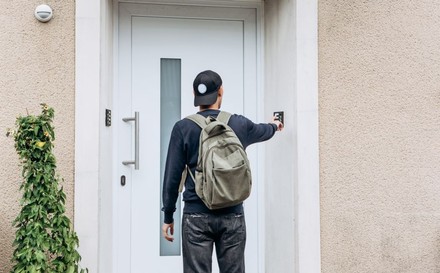 Mann mit Rucksack klingelt an Haustür