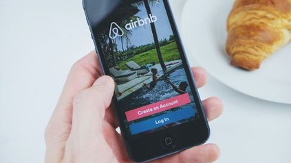 Eine Person hält ein Smartphone auf dem die Airbnb App aufgerufen ist