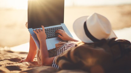 Eine Frau mit Laptop an einem Strand