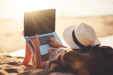 Eine Frau mit Laptop an einem Strand