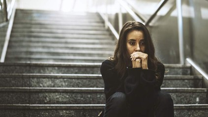 Eine verzweifelte Frau sitzt auf einer Treppe