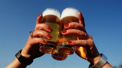 Hände halten drei Bier gegen den blauen Himmel