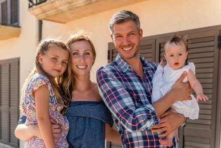 Eine Familie steht lächelnd vor einem Hotel