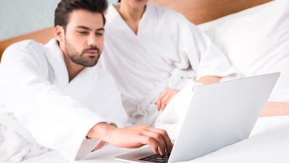 Ein Mann mit einem Laptop im Hotelzimmer