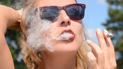 Frau mit Sonnenbrille raucht Zigarette