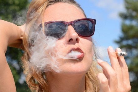 Frau mit Sonnenbrille raucht Zigarette