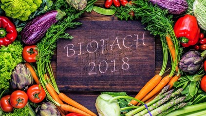 Ein Holzbrett auf dem BIOFACH 2018 steht umringt von frischem Gemüse