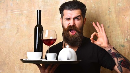 Kellner mit Tablett zwinkert in die Kamera