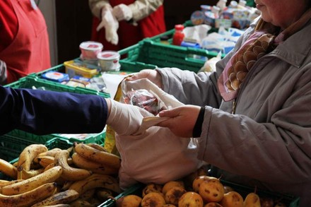 Eine ältere Dame hält eine Tasche auf während eine Mitarbeiterin etwas hineinlegt
