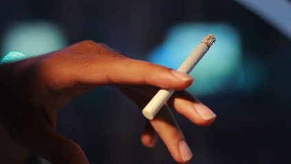 Eine Hand hält eine brennende Zigarette