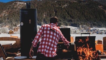 Ein Mann am Grill in einer verschneiten Landschaft am Kärntner Weissensee